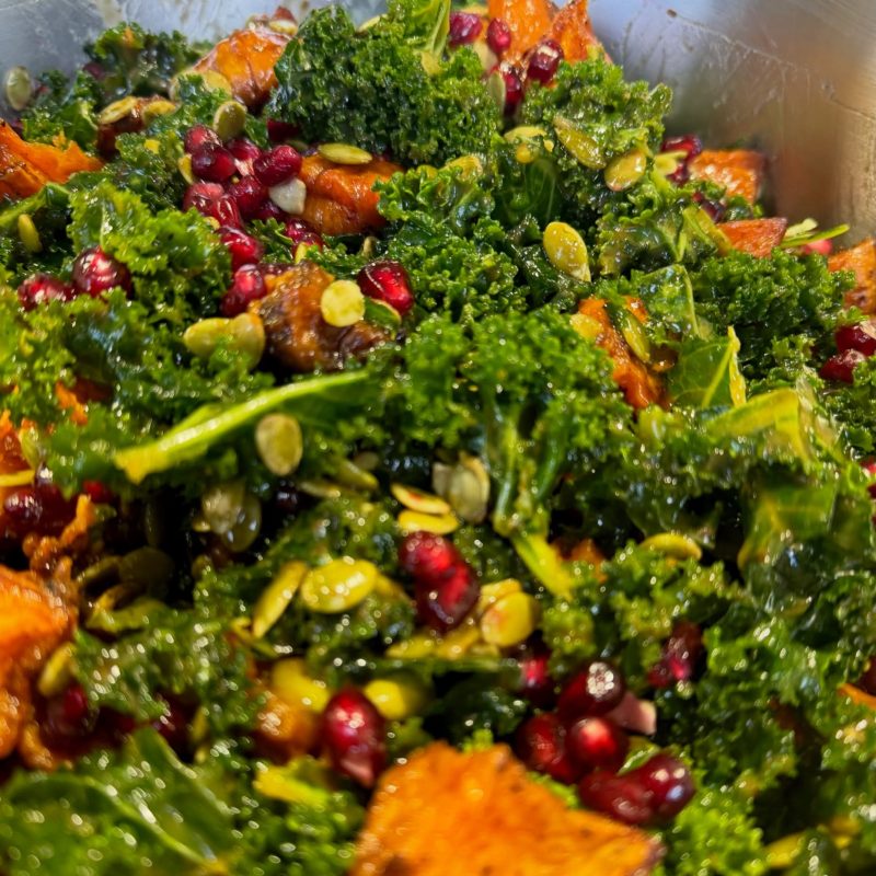 Kale, roast pumpkin and pomegranate salad tossed in the kitchen
