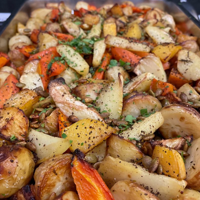 Tray of roast root vegetables with pepitas and herbs